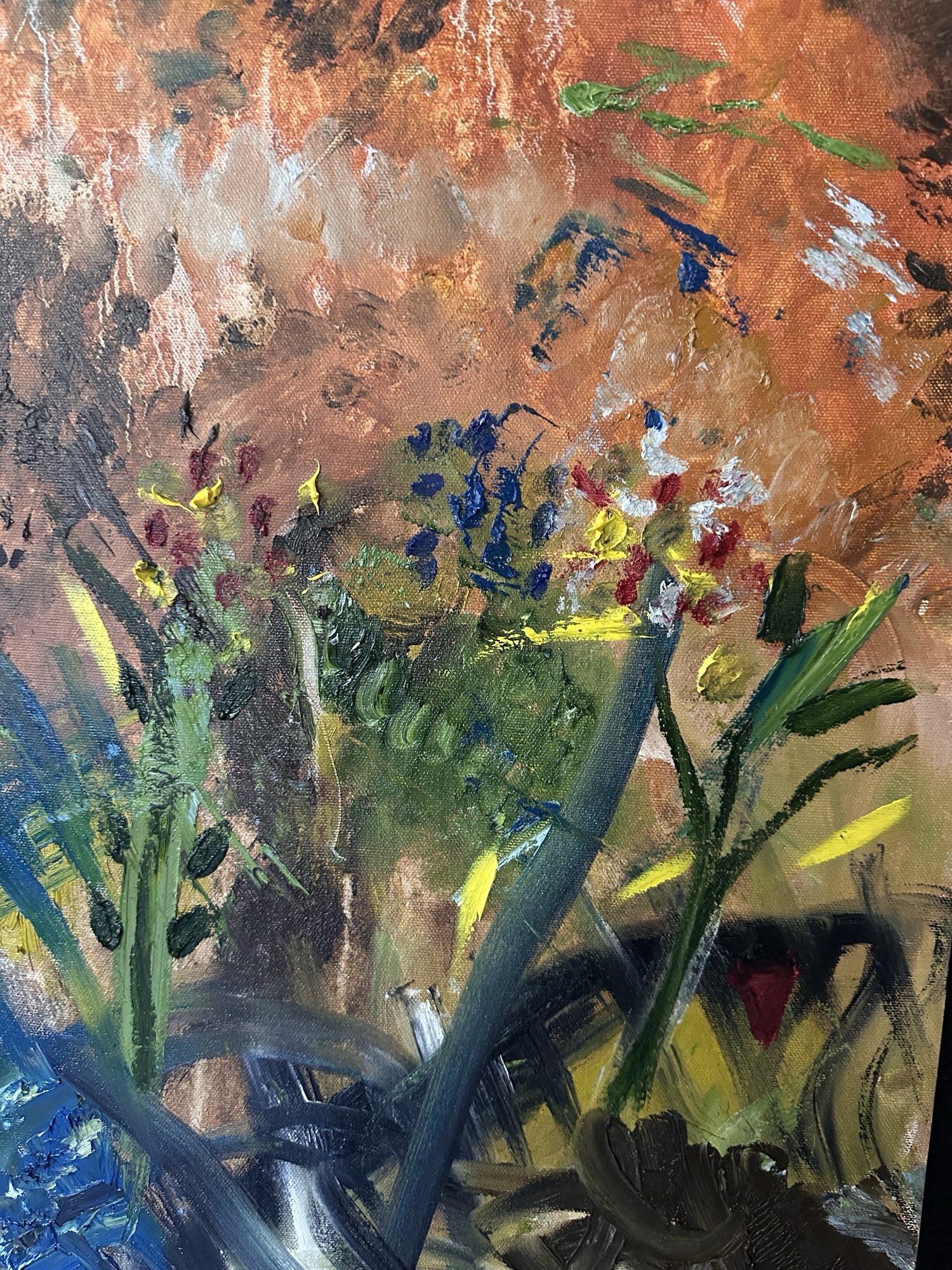 Detail: orange hillside with small blue, red and yellow wildflowers and thick green stems